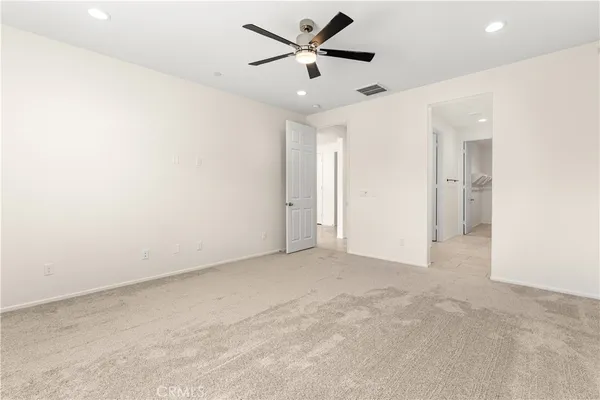 an empty room with chandelier fan and a ceiling fan