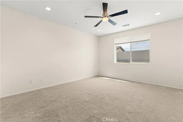 an empty room with a window and ceiling fan