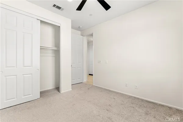 an empty room with closet and chandelier fan