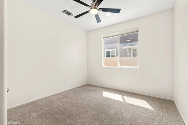 an empty room with a window and a fan