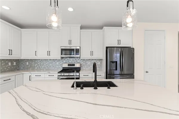 a kitchen with granite countertop a stove a sink and a refrigerator