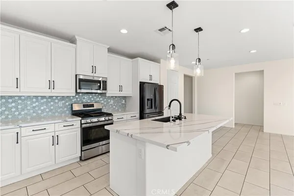 a kitchen with kitchen island granite countertop a sink a stove oven a counter top space and cabinets