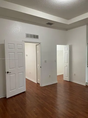 an empty room with wooden floor & closet area