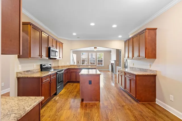 a large kitchen with stainless steel appliances granite countertop wooden floors and wooden cabinets