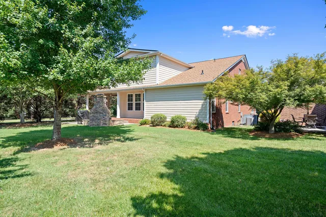 a backyard of a house with plants and large tree