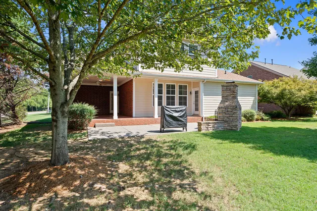 a view of a house with backyard and a tree