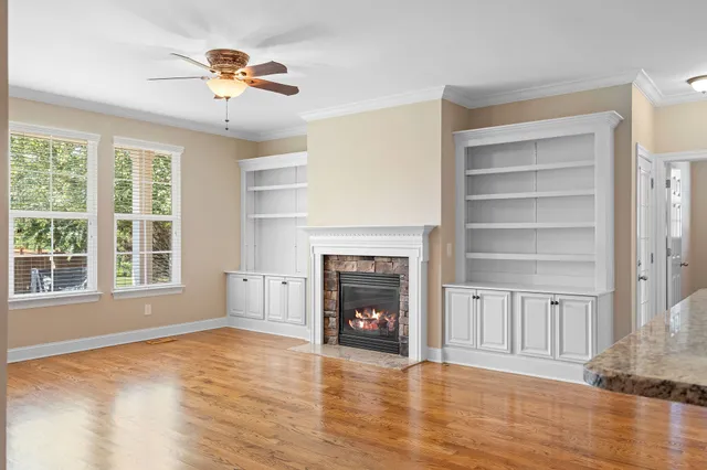 a view of an empty room with a fireplace and wooden floor