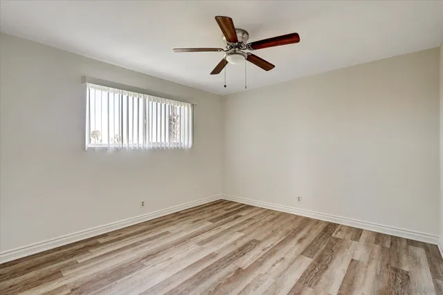 an empty room with a window and ceiling fan