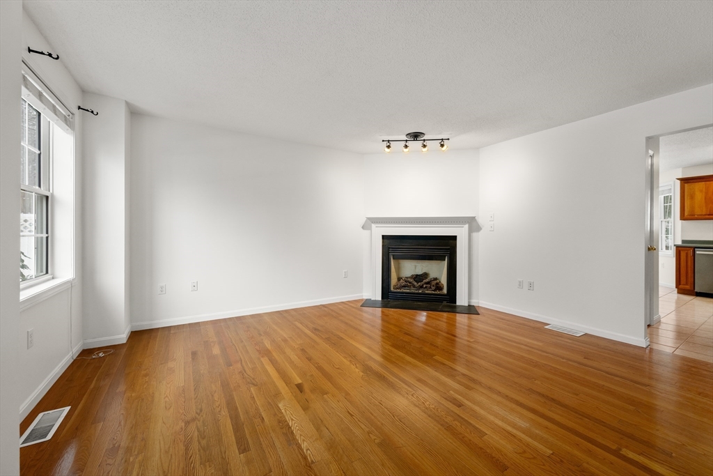 181 High Street, Unit 1 Andover, MA 01810 - Photo 3 of 21 a view of an empty room with wooden floor and a window