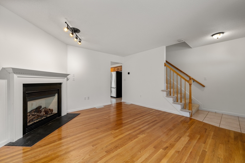 181 High Street, Unit 1 Andover, MA 01810 - Photo 5 of 21 a view of empty room with wooden floor and fireplace