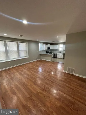 a view of empty room with wooden floor and window