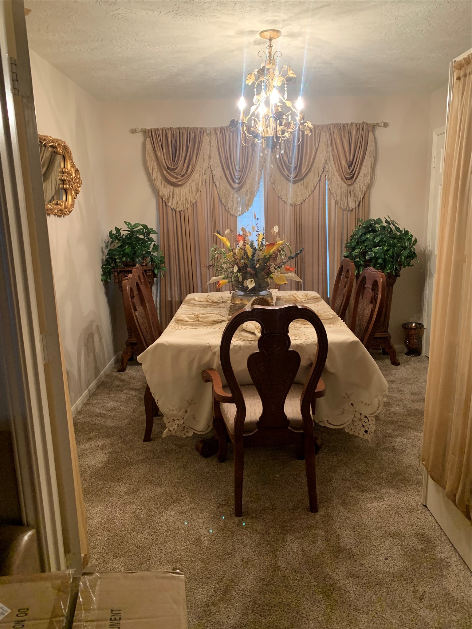 4630 Comal River Loop Spring, TX 77386 - Photo 6 of 12 This elegant dining room features a classic chandelier, a formal dining table with a floral centerpiece, and rich wood chairs. The space is warmly lit, with plush carpeting and decorative drapes framing the window, creating an inviting atmosphere.
