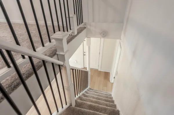 a view of staircase with railing and white walls