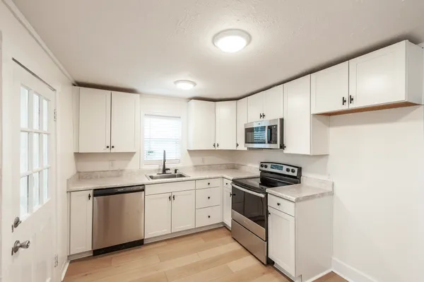 a kitchen with white cabinets stainless steel appliances and sink