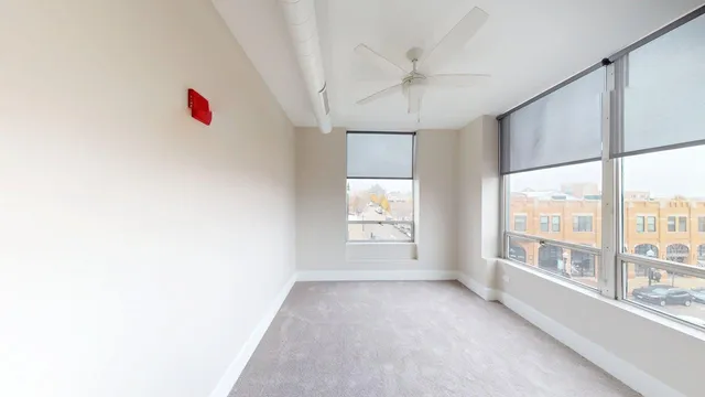 an empty room with chandelier fan and windows