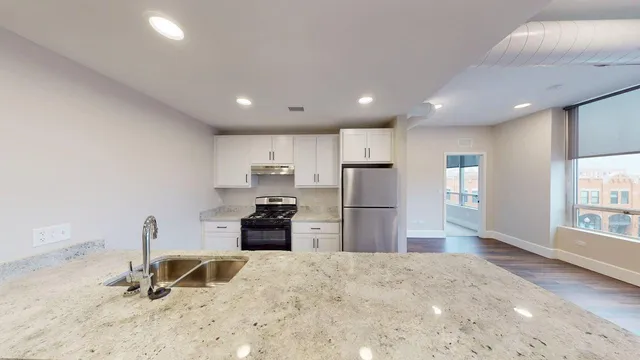a kitchen with granite countertop a stove sink and refrigerator