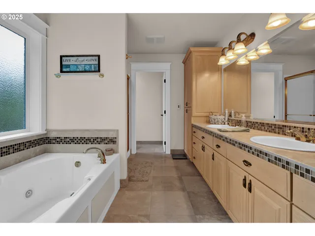 a bathroom with a tub a double vanity sink and a mirror