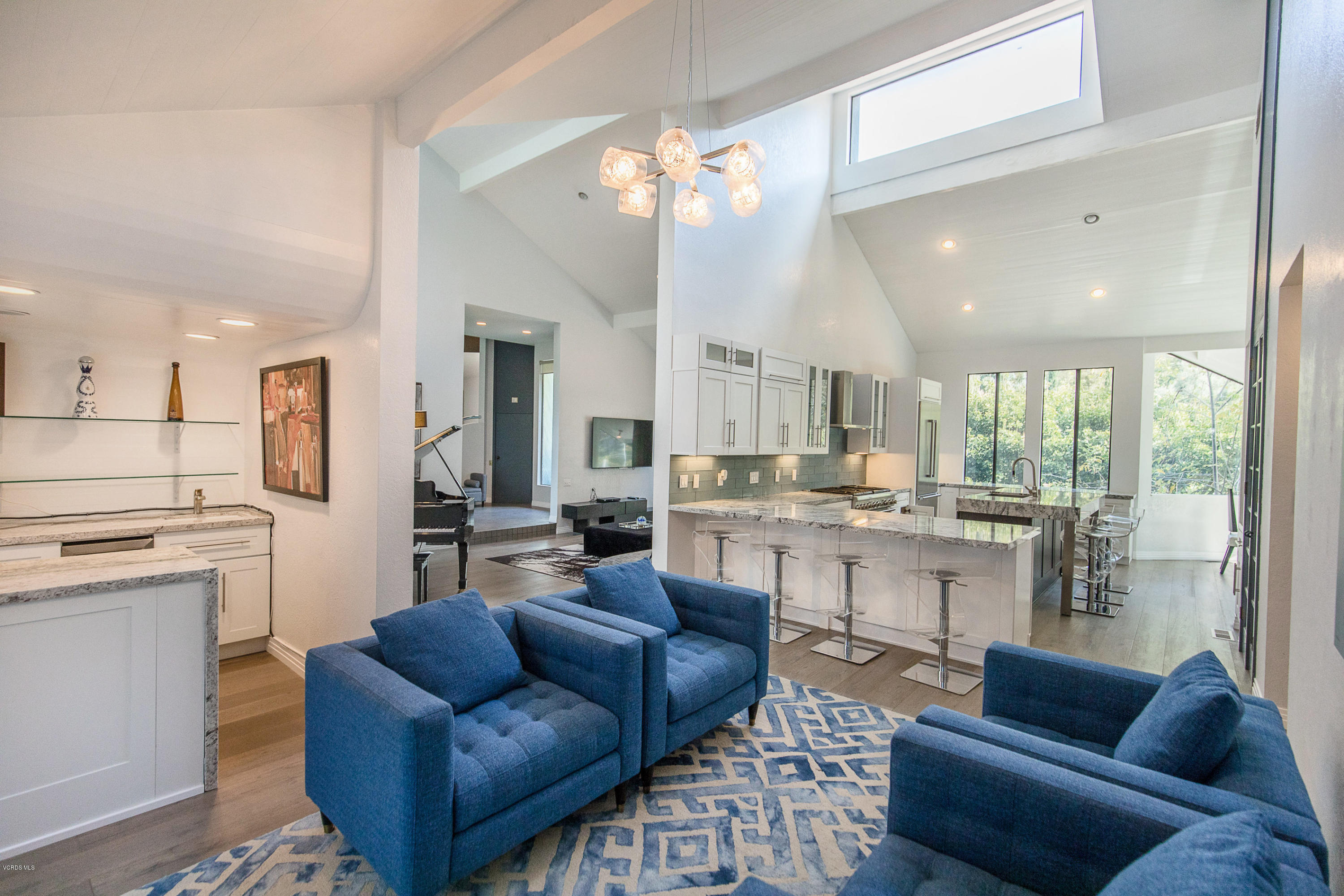 a living room with stainless steel appliances kitchen island granite countertop furniture and a large window
