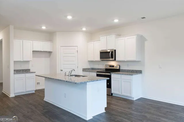 a kitchen with granite countertop a sink and a stove top oven with wooden floor