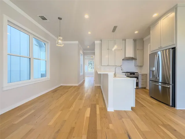 a kitchen with stainless steel appliances granite countertop a refrigerator a stove a sink dishwasher and a refrigerator with wooden floor