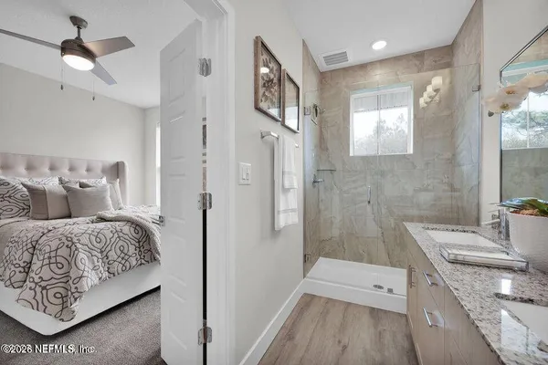 a en suite bathroom with a granite countertop double vanity sink a mirror and a shower
