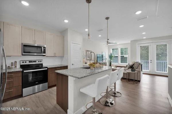 a kitchen with kitchen island granite countertop a stove a sink a dining table and chairs with wooden floor