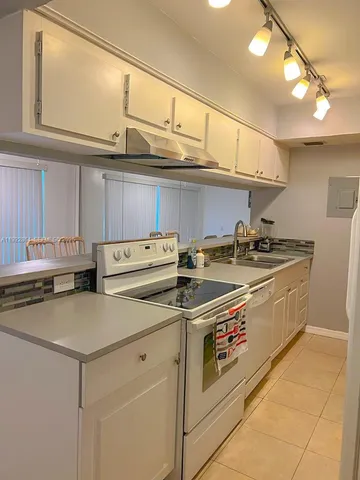 a utility room with stainless steel appliances granite countertop a sink and cabinets