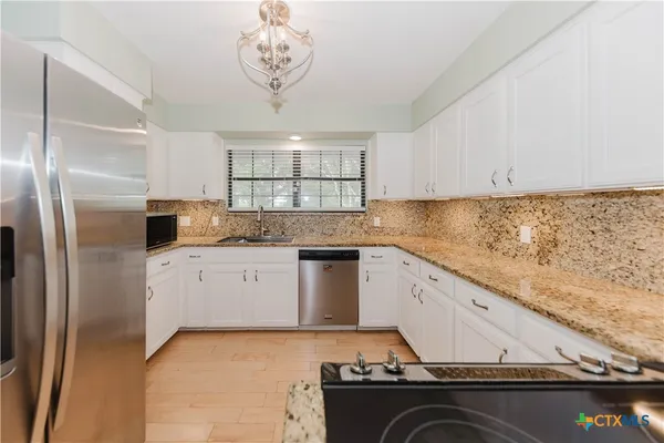 a kitchen with granite countertop white cabinets and white appliances