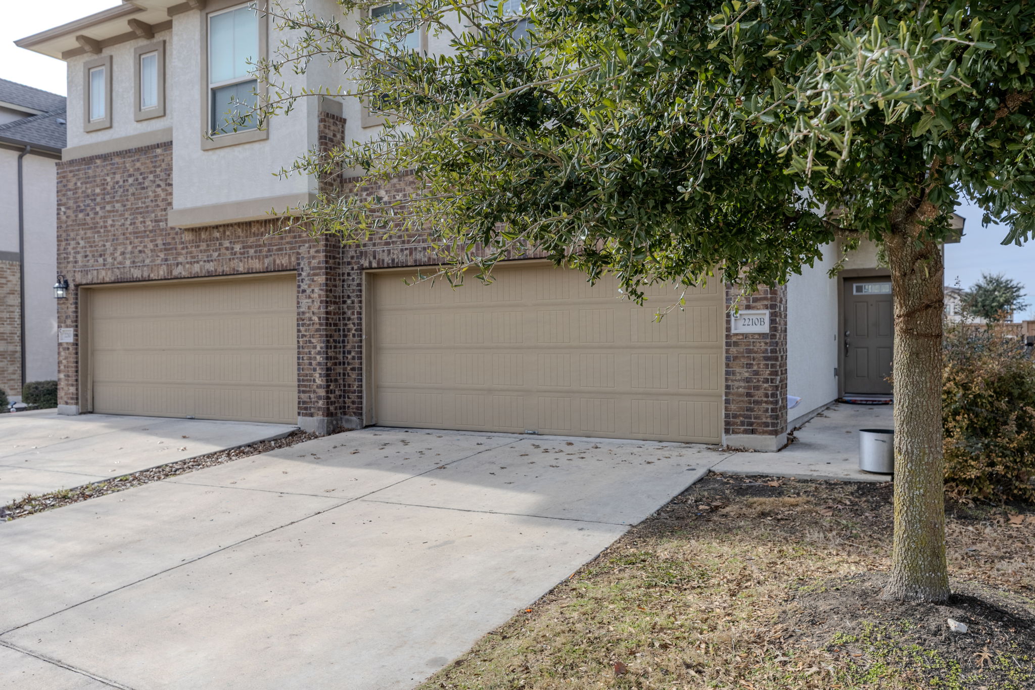 View of front of home with brick siding, driveway, an attached garage, and stucco siding