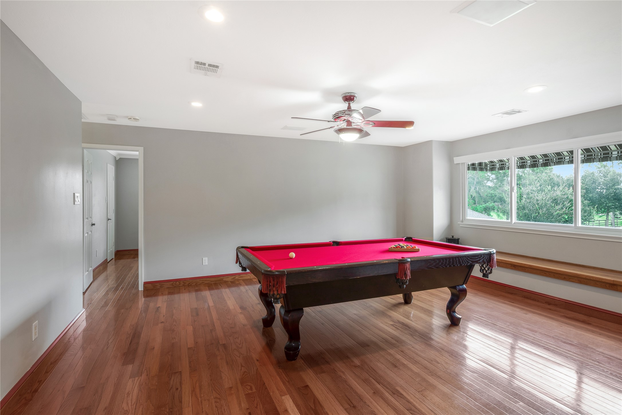 13914 Skinner Road Cypress, TX 77429 - Photo 19 of 50 Spacious game room with hardwood floors, a tray ceiling, pool table, and a wall of windows overlooking the backyard.