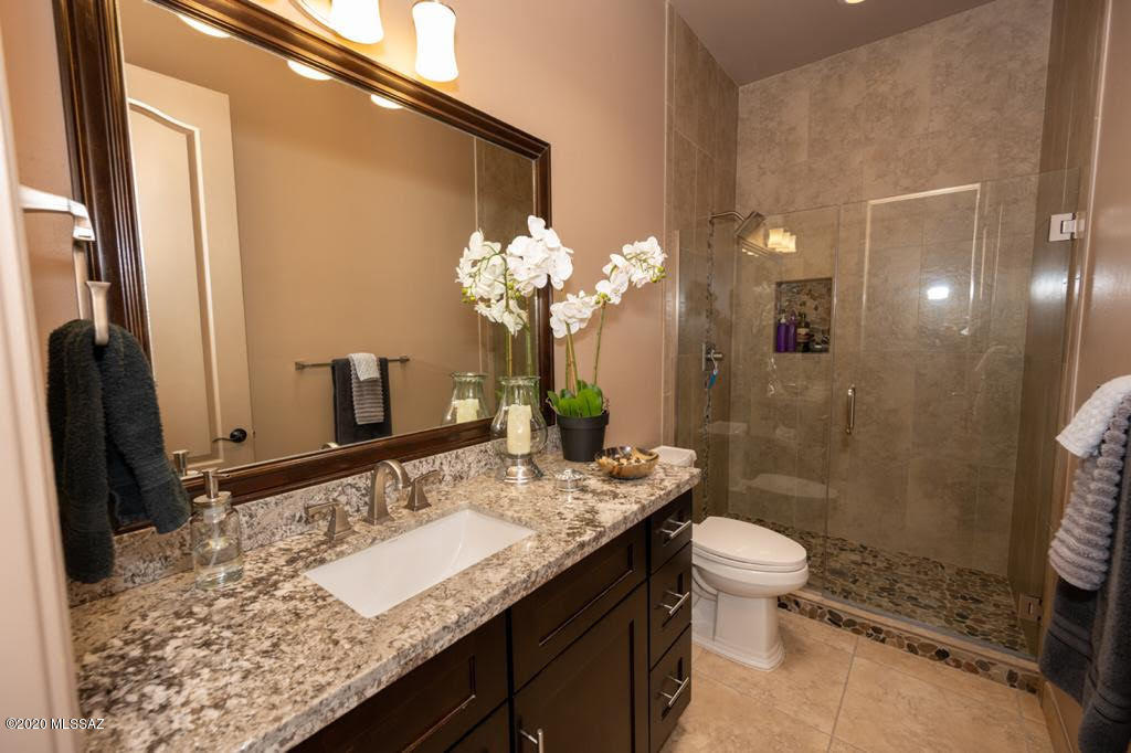 407 Camino Agua Fria Rio Rico, AZ 85648 - Photo 24 of 41 a bathroom with a granite countertop sink a toilet a mirror and shower