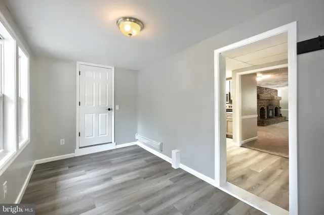 a view of an empty room with window and wooden floor