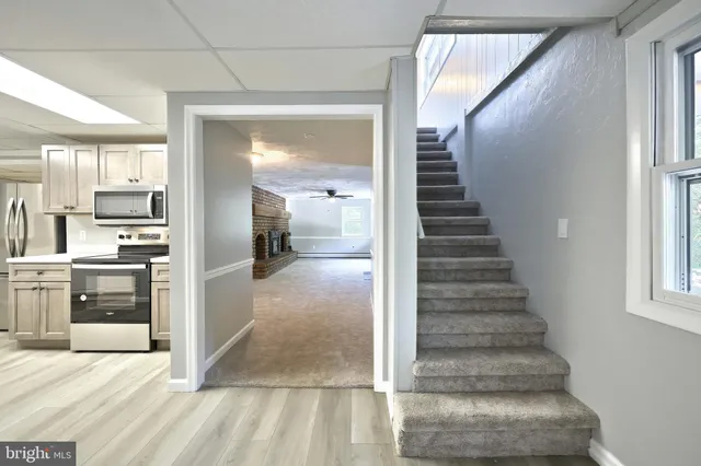 a view of an empty room with window and chandelier fan