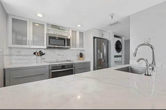 a kitchen with stainless steel appliances granite countertop a sink a stove a microwave and a refrigerator