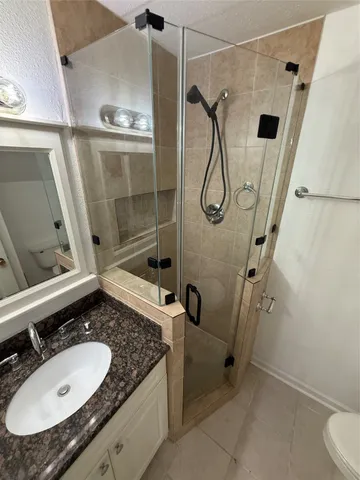 a bathroom with a granite countertop sink a mirror and shower
