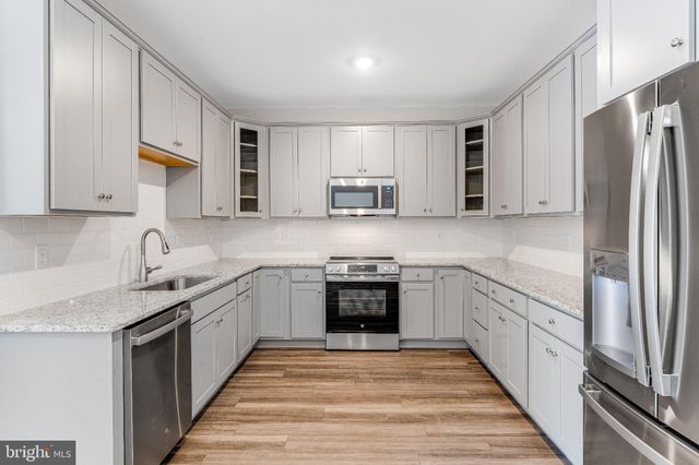 a kitchen with stainless steel appliances granite countertop a refrigerator and a stove top oven