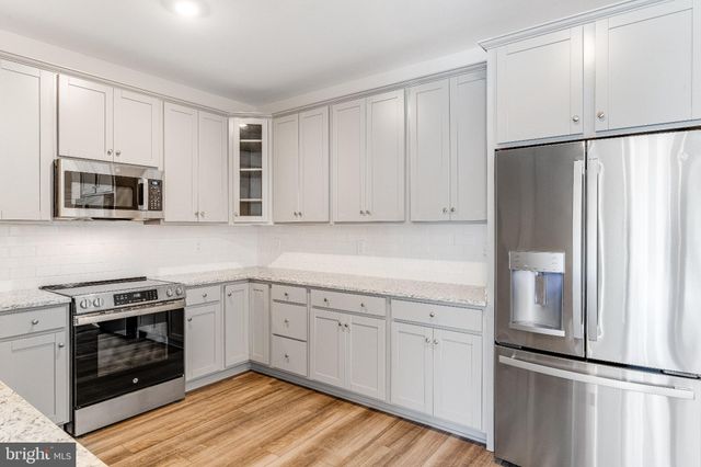 a kitchen with cabinets stainless steel appliances and wooden floor