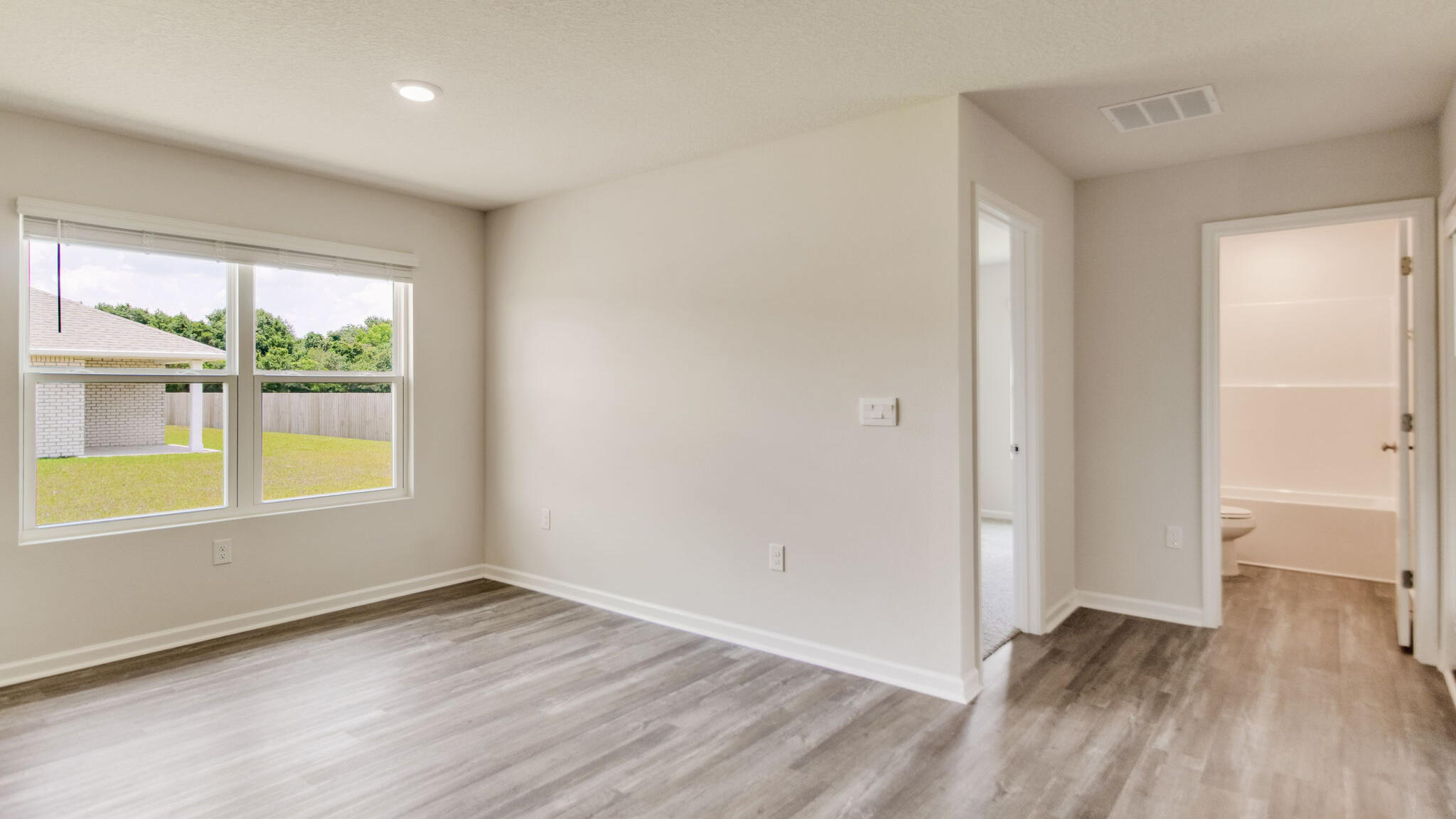 5621 Thatcher Road Crestview, FL 32539 - Photo 8 of 30 an empty room with wooden floor and windows