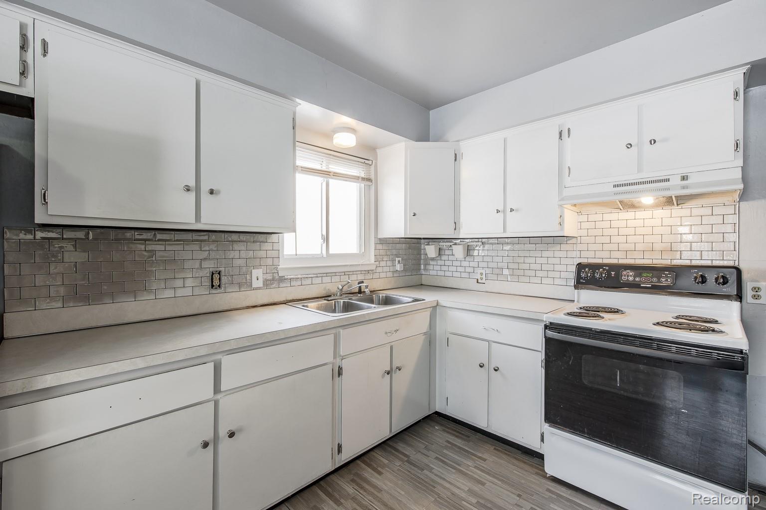 8670 North Eston Road Clarkston, MI 48348 - Photo 6 of 29 Kitchen featuring white electric range, white cabinetry, light countertops, light wood-style floors, and backsplash