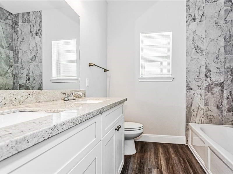 7838 Booker Street, Unit B Houston, TX 77028 - Photo 18 of 28 a bathroom with a granite countertop sink toilet a large mirror a bathtub and window