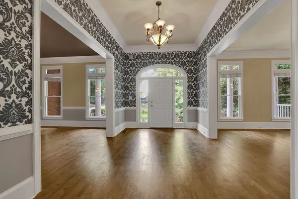 a view of a room with wooden floor chandelier and windows