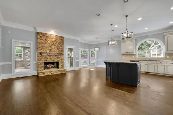 an open kitchen with a fireplace and wooden floor