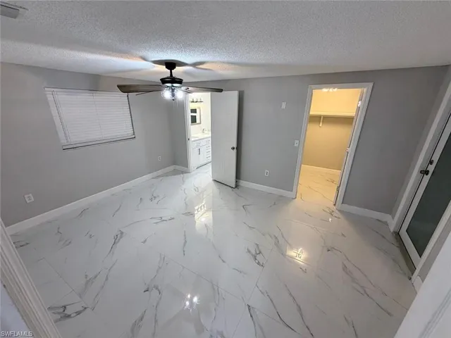 an empty room with chandelier fan and windows