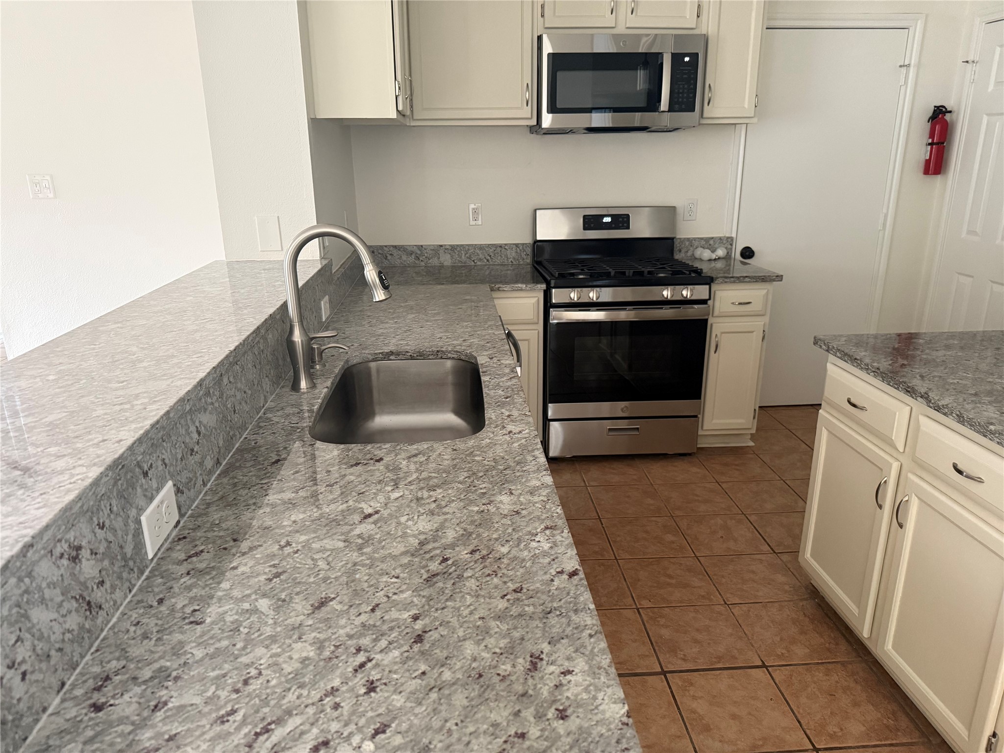 16910 Isle Of Man Road Pflugerville, TX 78660 - Photo 6 of 13 Kitchen featuring light-toned cabinetry, stainless steel appliances, granite countertops, an undermount sink with a gooseneck faucet, and ceramic tile flooring