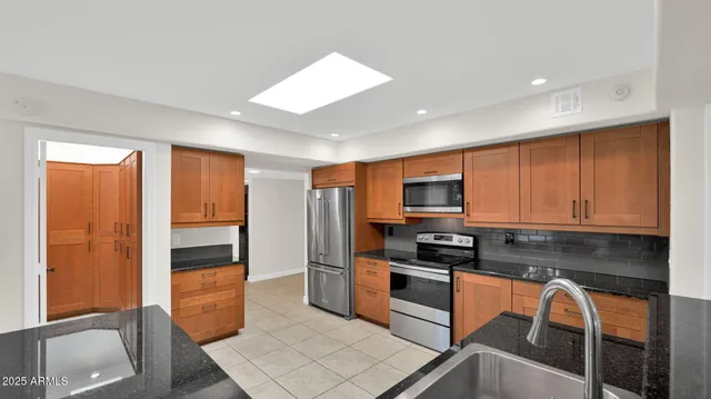 a kitchen with stainless steel appliances granite countertop a refrigerator and a stove top oven