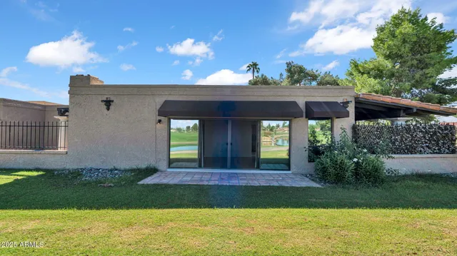 a view of a house next to a yard with plants and large trees