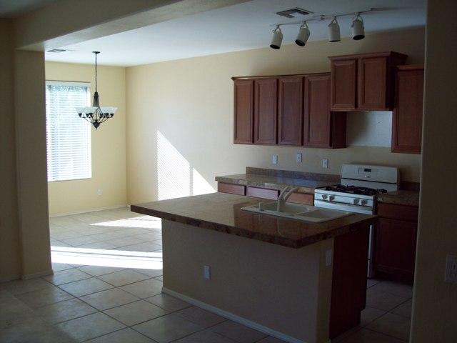 15331 West Calavar Road Surprise, AZ 85379 - Photo 7 of 15 a kitchen with kitchen island granite countertop a sink stove and cabinets
