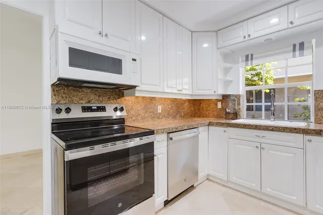 a kitchen with white cabinets and appliances