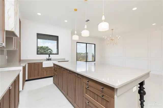 a large kitchen with granite countertop a sink dishwasher and white cabinets with wooden floor