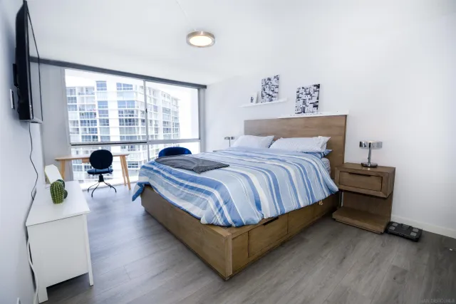 a bedroom with a bed a couch and a flat tv screen on dresser
